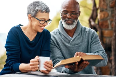 Two seniors reading together in an outdoor space