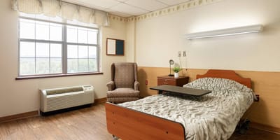 Complete Care at Berkshire, Nursing Home in Reading, PA — Cozy bedroom setup with bed and armchair