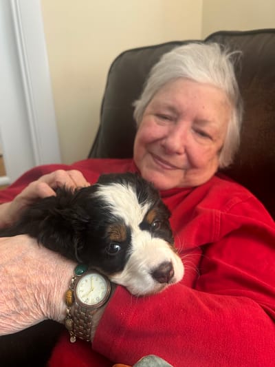 A resident holding a puppy while smiling