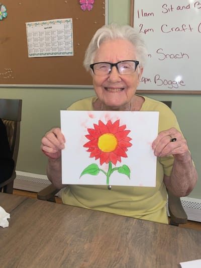Resident proudly displaying a colorful flower painting