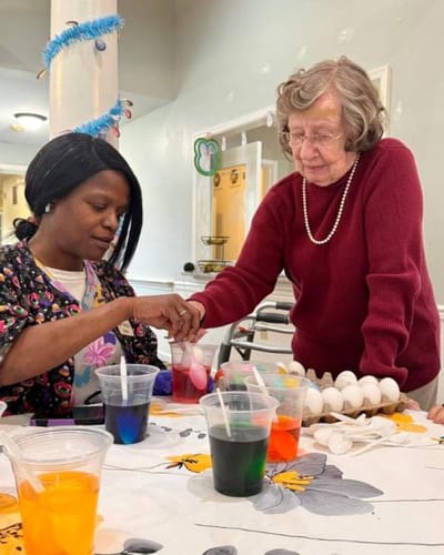 Resident and staff coloring eggs during an activity