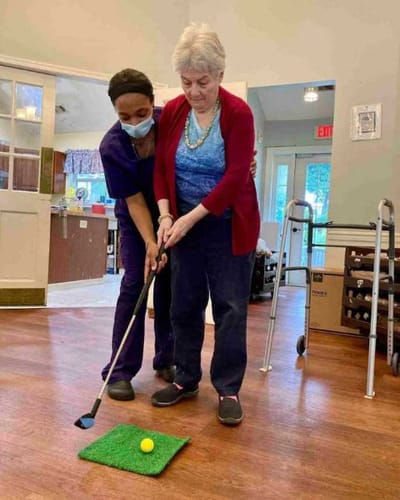 Staff assisting a resident with indoor golf activity