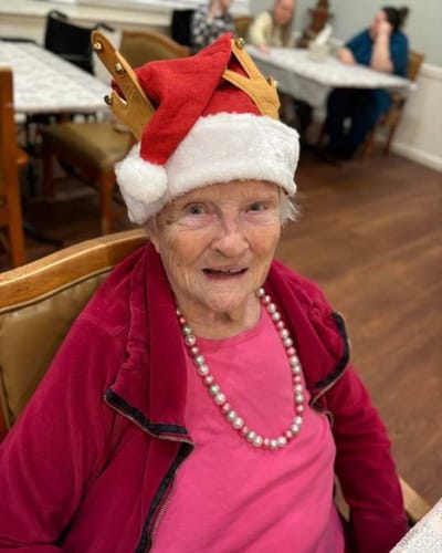 Senior resident wearing a festive crown and necklace
