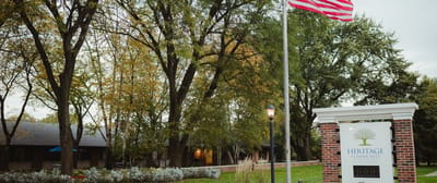 Exterior view of Heritage Community with flag and trees