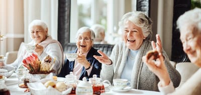 Residents enjoying tea and laughter at a table
