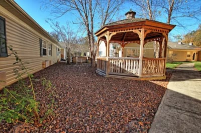 A gazebo surrounded by fallen leaves in a courtyard
