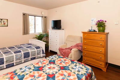 Private resident room with two beds and a TV