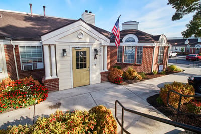 Exterior view of the facility entrance with flowers and flag