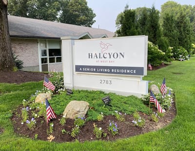 Sign for Halcyon at West Bay with flowers and flags