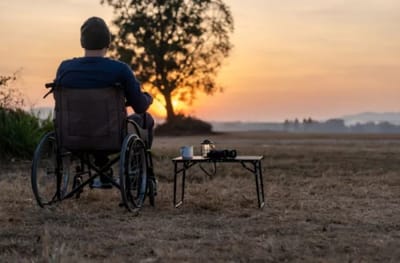 A person in a wheelchair watching a sunset outdoors