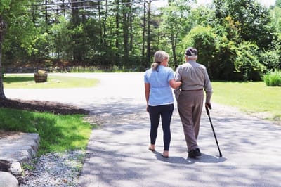 Pond View Acres, assisted living in Barrington, NH — Caregiver assisting elderly resident along a pathway