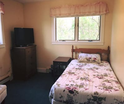 A private bedroom with floral bedding and a TV