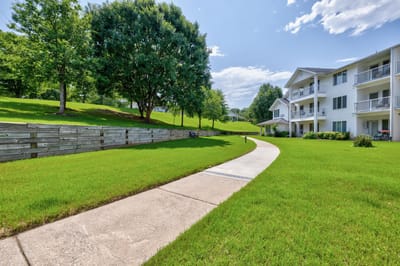 Pathway leading through a grassy area with buildings in background