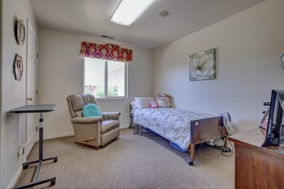 A cozy resident room featuring a bed and recliner chair