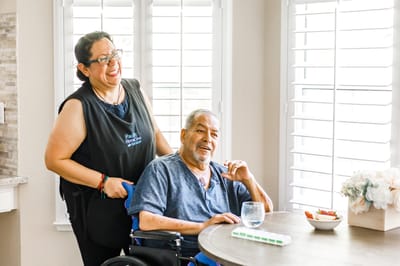 A staff member assisting a resident at a dining table