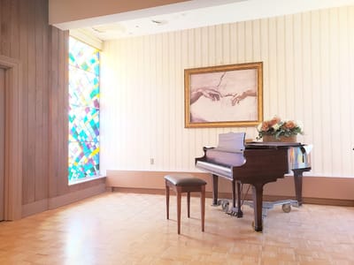 Interior view of a music room with a piano and stained glass