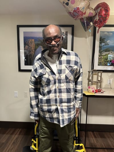Resident celebrating with balloons in a common area.