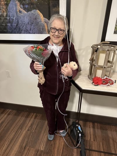 Resident celebrating with flowers and balloons.