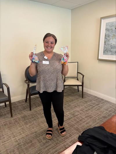 Staff member holding colorful awards in a common area.