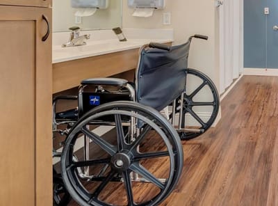 Wheelchair next to a bathroom sink in a care facility