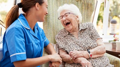 Caregiver and elderly resident sharing a joyful moment.