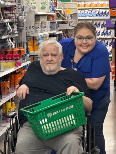 Senior resident with staff member shopping together.