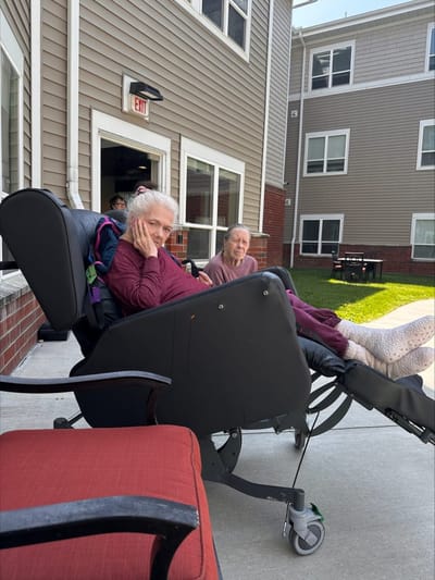 Residents enjoying time outdoors in comfortable chairs.