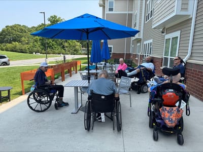 Residents enjoying time outdoors under an umbrella.