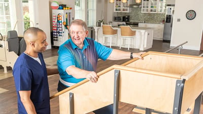 Staff assisting a resident with rehabilitation equipment.