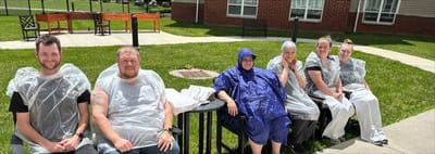 Residents and staff enjoying outdoor time in rain gear.