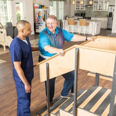 Therapist assisting a senior on rehabilitation stairs.