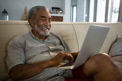Senior man using a laptop in a cozy living space.