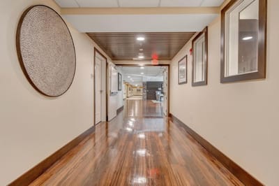 Well-lit hallway with wooden floors and art