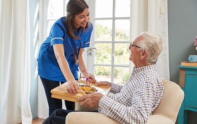 Staff serving food to a resident in a cozy interior
