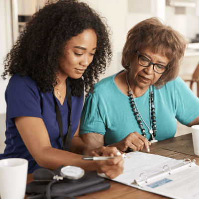 Nurse assisting elderly resident with paperwork.
