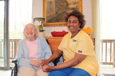 Staff member assisting a smiling resident.