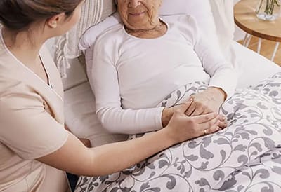 Caregiver providing comfort to a senior resident in bed