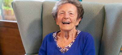 Smiling elderly resident sitting in a comfortable chair