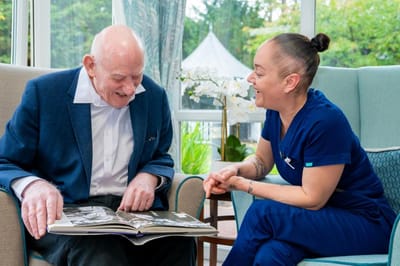A resident and staff member enjoying a photo album together