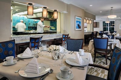 Dining room setup with staff preparing food in the kitchen