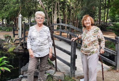 Two residents enjoying a garden area by a bridge