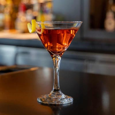 A cocktail in a martini glass with lemon twist