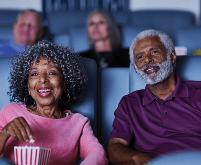 Two seniors enjoying a movie with popcorn