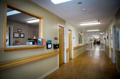 A corridor in a senior living facility with residents and staff.