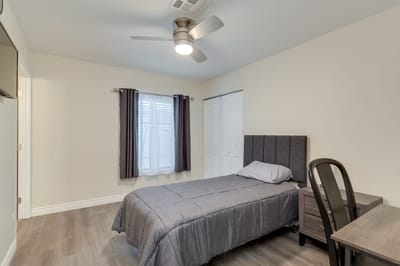 A simple interior view of a resident's room with a bed and desk