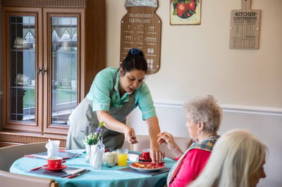 Staff serving food to a resident during mealtime
