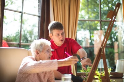 Resident engaged in painting activity with staff member