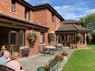 Exterior view of the nursing home with residents enjoying the patio