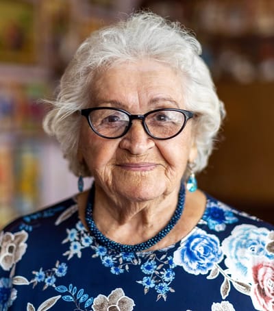 An elderly woman smiling in a floral shirt