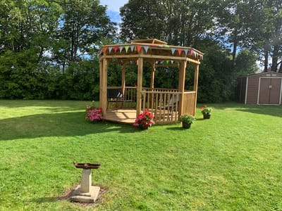A gazebo surrounded by flowers in a grassy area